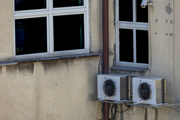 Old damaged air conditioners requiring maintenance and fungicides hanging on the external wall of a...