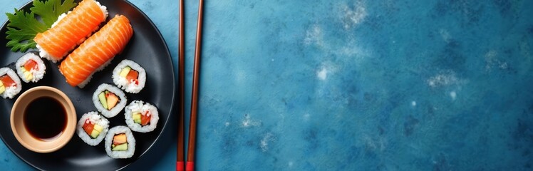 Assorted sushi maki rolls arranged on black plate with soy sauce. Japanese cuisine, rice seafood, culinary art. Top view, blue stone background, copy space, food photography.