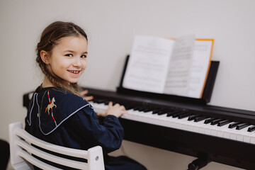 Young Girl Playing Piano with Sheet Music