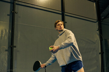 Dynamic young sportsman mastering the art of padel on a vibrant court