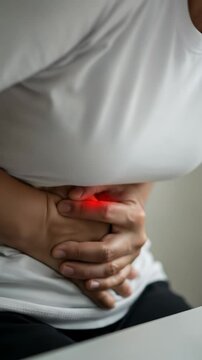 Woman suffering from abdominal pain and upset stomach, with hands clutching her belly in discomfort concept footage.