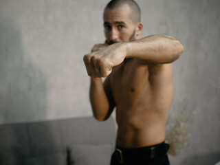 A young attractive man trains boxing at home after work.