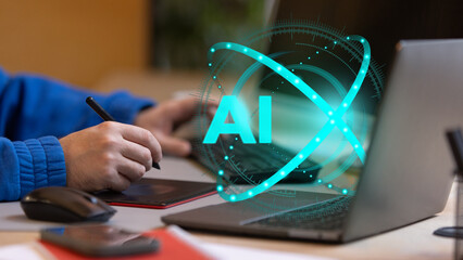 Person interacts with digital pad while AI hologram glows beside laptop, symbolizing artificial...