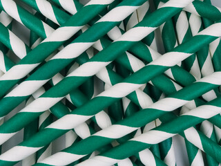 Full frame of many green and white striped paper straws.