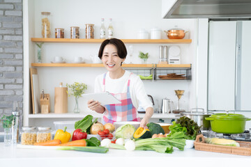 キッチンでタブレットを使うミドルの主婦