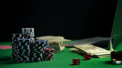 Stack of poker chips, dice, and money on table beside laptop, online casino - Powered by Adobe