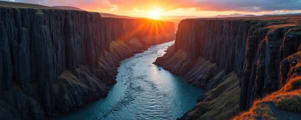 Studlagil canyon, Iceland. Basalt columns riverbed gorge with mountain range at sunrise. Scenic landscape with water flow. Travel destination adventure, explore nature. High cliffs reflect warm