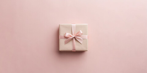 Gift box with a ribbon on a soft pink background.
