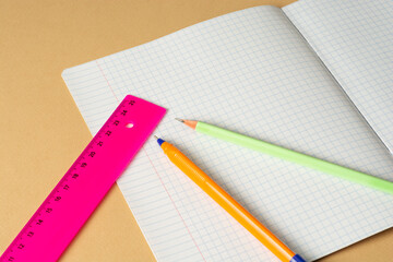 Thin notebook in a cage, pencil, pen and ruler. Stationery for students and schoolchildren. Copy space, macro