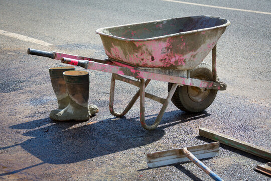 Wheelbarrow, tools and boots of concrete worker