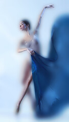 Poised faded dancer captured mid turn with vibrant blue silk, surrounded by cool hues and soft...