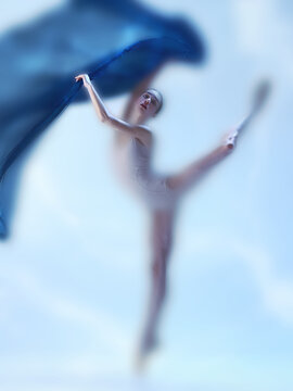 Fototapeta Contemporary faded ballet, showing dancer mid leap with sweeping motion of blue fabric, against a soft cloudy background. Concept of visual identity for ballet school enrollment promotions