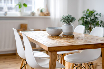 Simple dining space with wooden table, white chairs, ceramic bowl, and greenery, lit by soft window light from the right