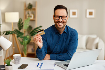 Happy entrepreneur making online payment with credit card at home office
