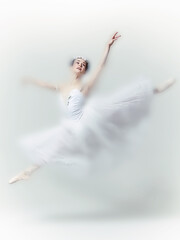 Solo faded ballerina captured mid leap in pure white costume, exuding lightness, precision, and...