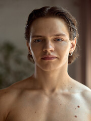 Inclusive beauty. Young man with visible skin features, birthmark, looks calmly at the camera....