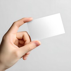 Obraz premium Close-up of hand holding blank white business card minimalist, clean design, neutral background.