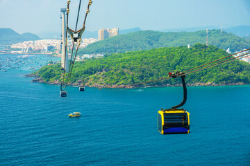 Aerial view of cable car gondola gliding over turquoise sea and green tropical island. Longest Hon...