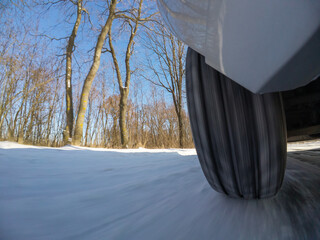 Car wheel on a snowy winter road. A moving wheel on a winter road, highlighting the difficulties...