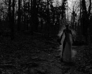 A sinister figure with antlers enveloped in mist standing in a forest