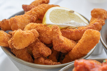 Savor delicious golden fried fish fillets served with a zesty lemon slice on the side