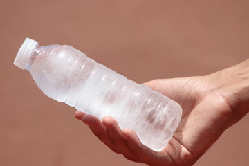 Hand holding a bottle of frozen water