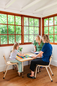 Girl speech therapist and parent talking together at table
