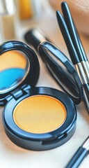 Close-up of makeup products, including a round, gold-toned eyeshadow compact, a small mirror, and makeup brushes