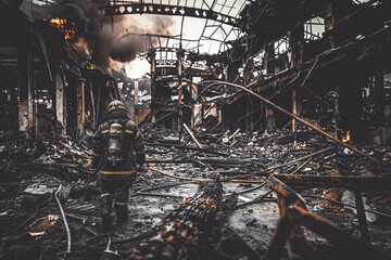 Firefighter walking through the wreckage of a burnt industrial building