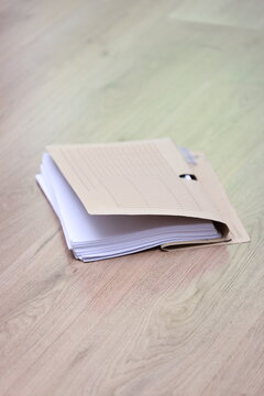 single file lies on the wooden floor, filled with lots of paper, neutral wrapping in light brown