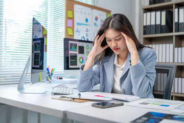A woman is sitting at a desk with a computer monitor