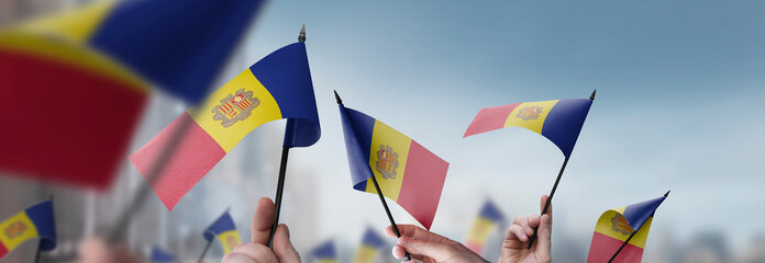 Andorra flags in their hands on a blurred urban background