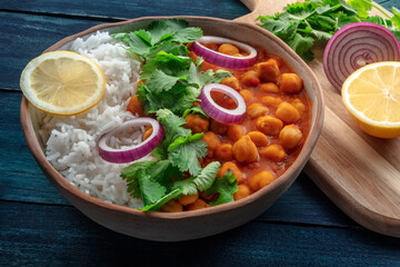 Chana masala, chickpea curry, traditional Indian dish,with ingredients on a rustic background