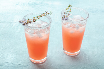 Salty Dog cocktail with fresh grapefruit juice, lime juice, and thyme, served with ice in a Collins...