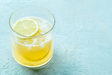 A glass of lemonade, a mocktail with lemon juice, on a blue background, summer cold drink, with copy space