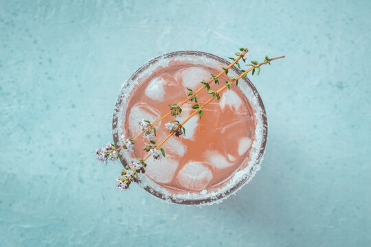 Salty Dog cocktail with fresh grapefruit juice, lime juice, and thyme, overhead flat lay shot on a blue slate background