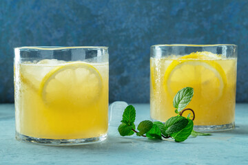 Glasses of lemonade with mint, a mocktail with lemon juice, on a blue background, summer cold...