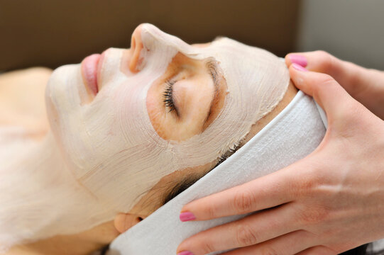 Woman relaxes as a beautician applies a fask mask during a beauty treatment
