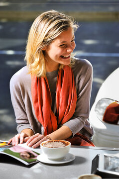 young woman sitting outdoors at a cafe with a coffee