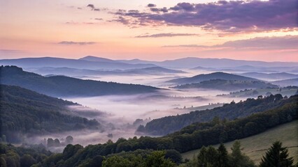 Fototapeta premium A scenic view of mountains and valleys shrouded in fog at sunrise