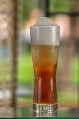 Glass of cold craft beer on bar, soft blurred background