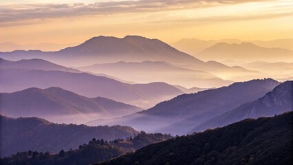 Obraz premium A panoramic view of misty mountain ranges under a soft, colorful sky at dusk