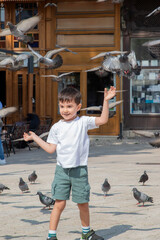 Smiling Boy Enjoying Pigeons in City Square on Sunny Day, Sarajevo city.