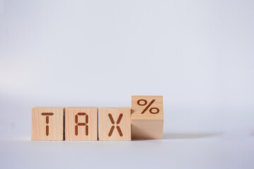 Wooden blocks spell out TAX, with an additional block showing a percentage sign, representing tax rates.