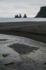 Iconic Reynisdrangar Sea Stacks and Black Sand Beach in Iceland with a Gentle Stream Flowing...