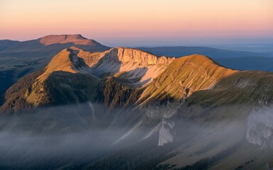 Fototapeta premium Majestic Mountain Peaks Bathed in Golden Sunrise Light Above Wispy Clouds