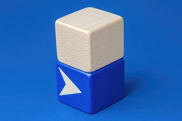 Two light beige wooden cubes, stacked, with a blue cube at the bottom bearing a white arrow pointing right