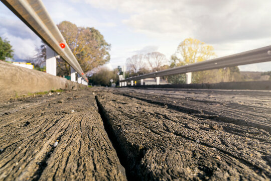 A ground level view of weathered wooden planks on a road bridge