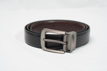 Coiled black perforated leather belt with a sleek gunmetal rotating buckle, offering versatile...