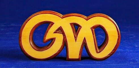 Wooden, carved letters of a stylized, intertwined "GWD" design,  in light yellow/gold,  with a dark brown/reddish wood trim